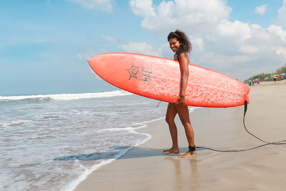 Girl on the beach with an orange surf board SurfWG Bali surf camp our guest on the beach with an orange surf board