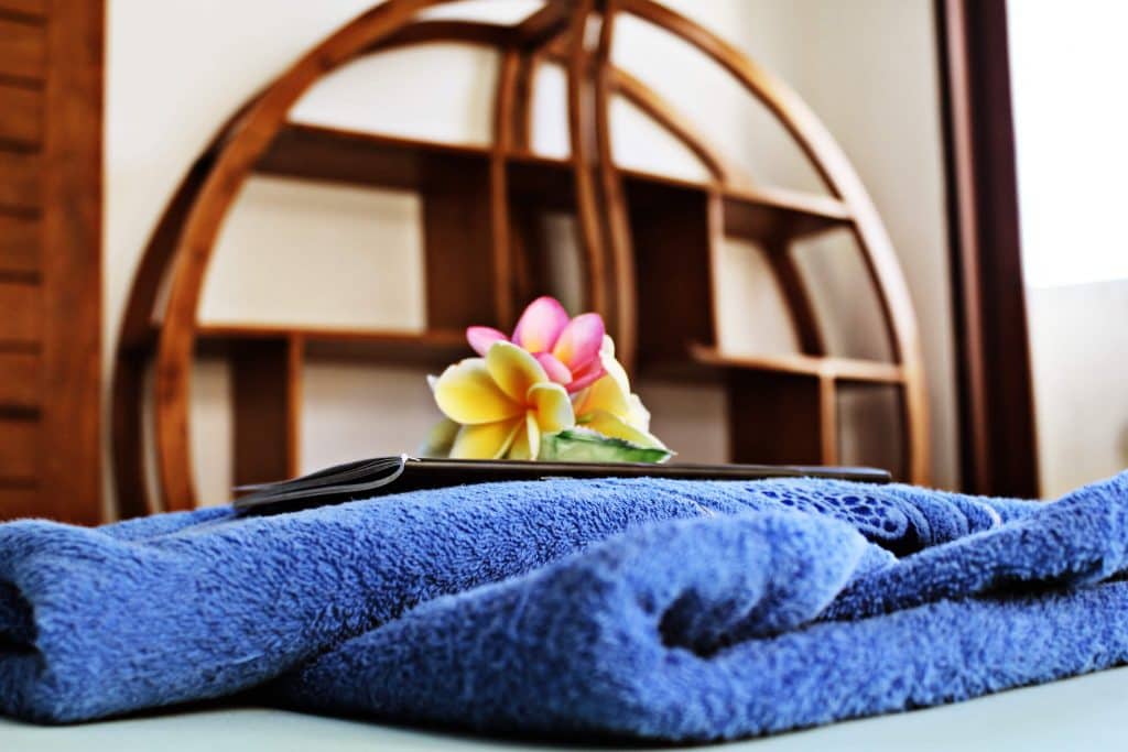 SurfWG-towel-room SurfWG towel with yellow and pink flower on top of a bed