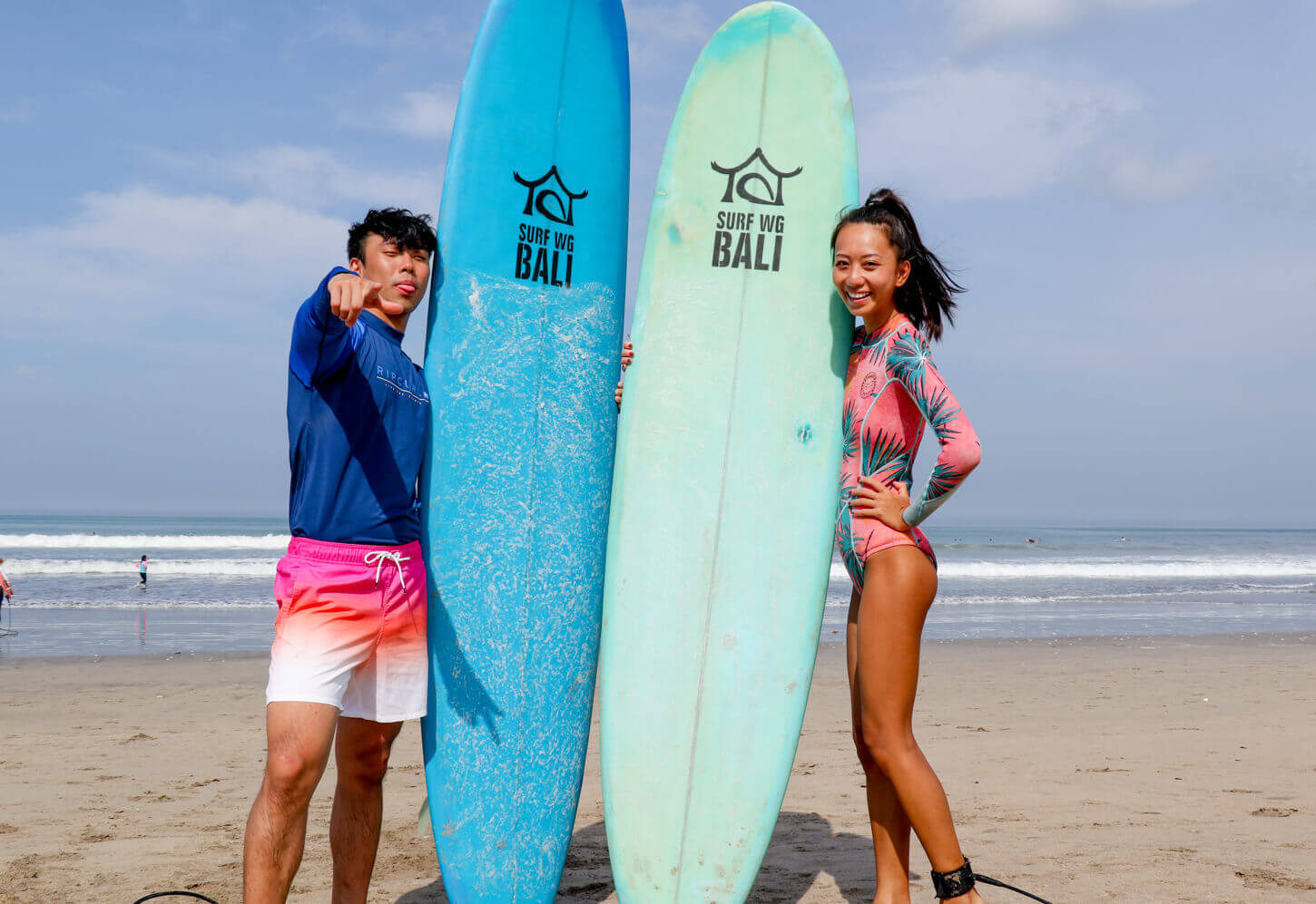 SurfWG two guests with surf boards learning surfing smiling on the beach Learn to surf in Bali with uóur beginner class in Bali SurfWG