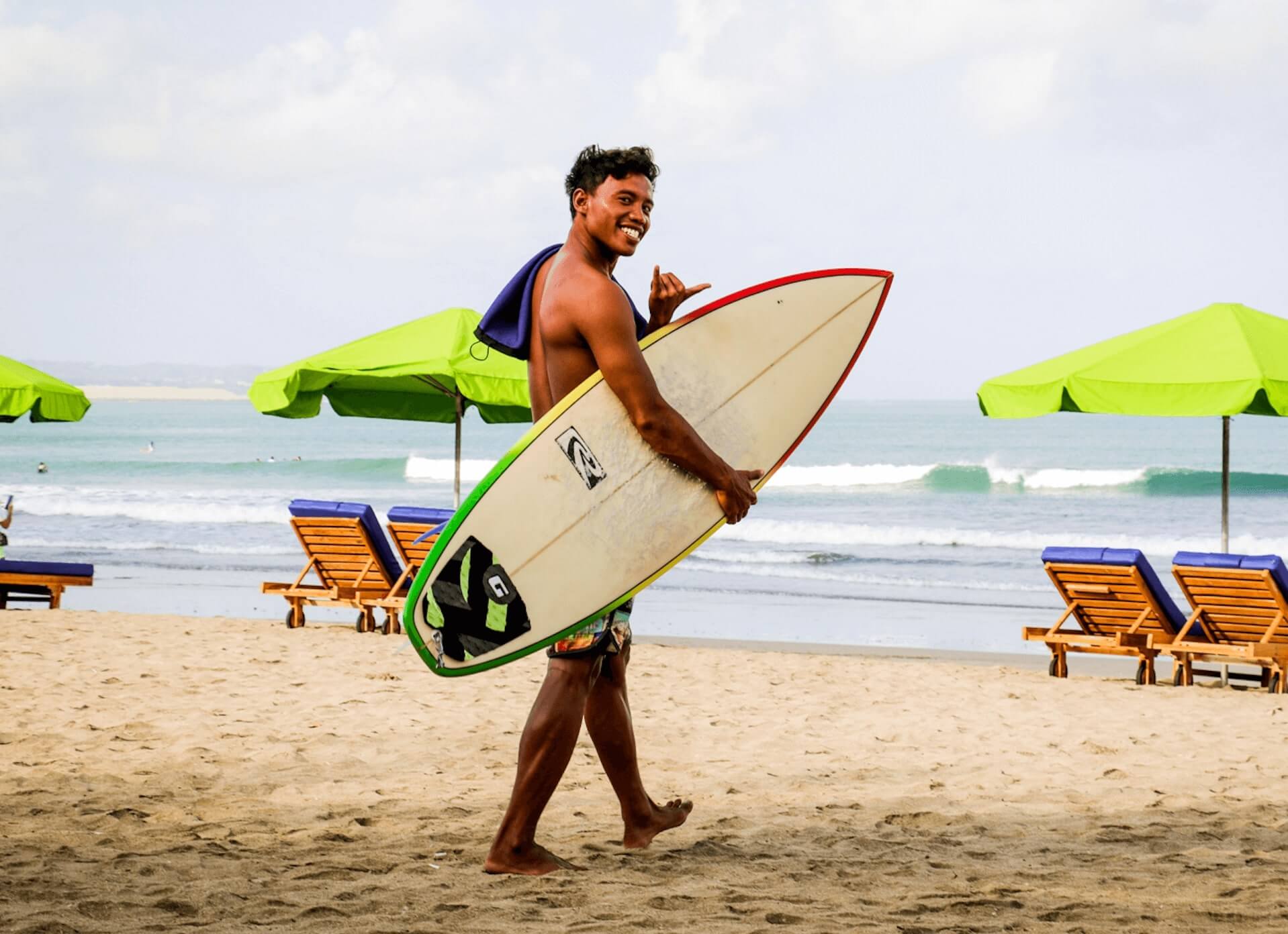 Surf school SurfWG Bali Surfguide Ronaldo with surfboard on the bway to the beach shakka